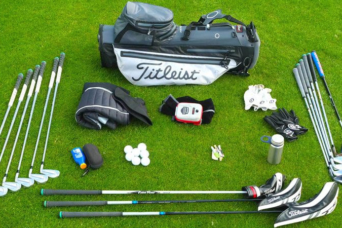 Zestaw podstawowego wyposażenia golfisty obejmujący torbę golfową, kije, piłki, rękawiczki i akcesoria do gry na zielonym polu